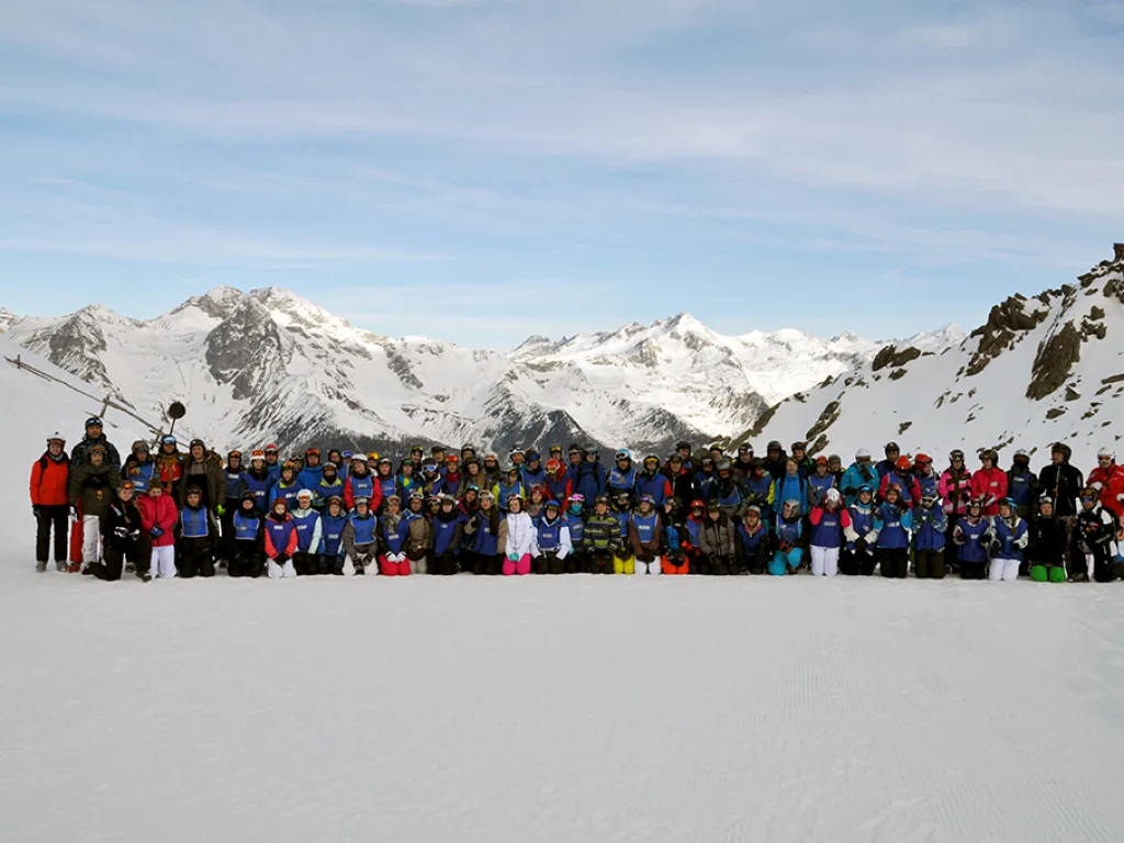 Große Gruppe posiert vor dem Bergpanorama.